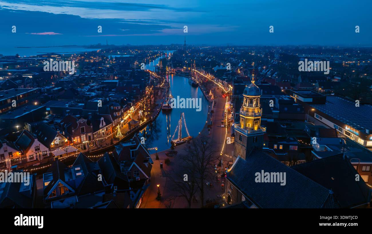 Vista notturna della città con Church Tower illuminata e barche nel porto Foto Stock