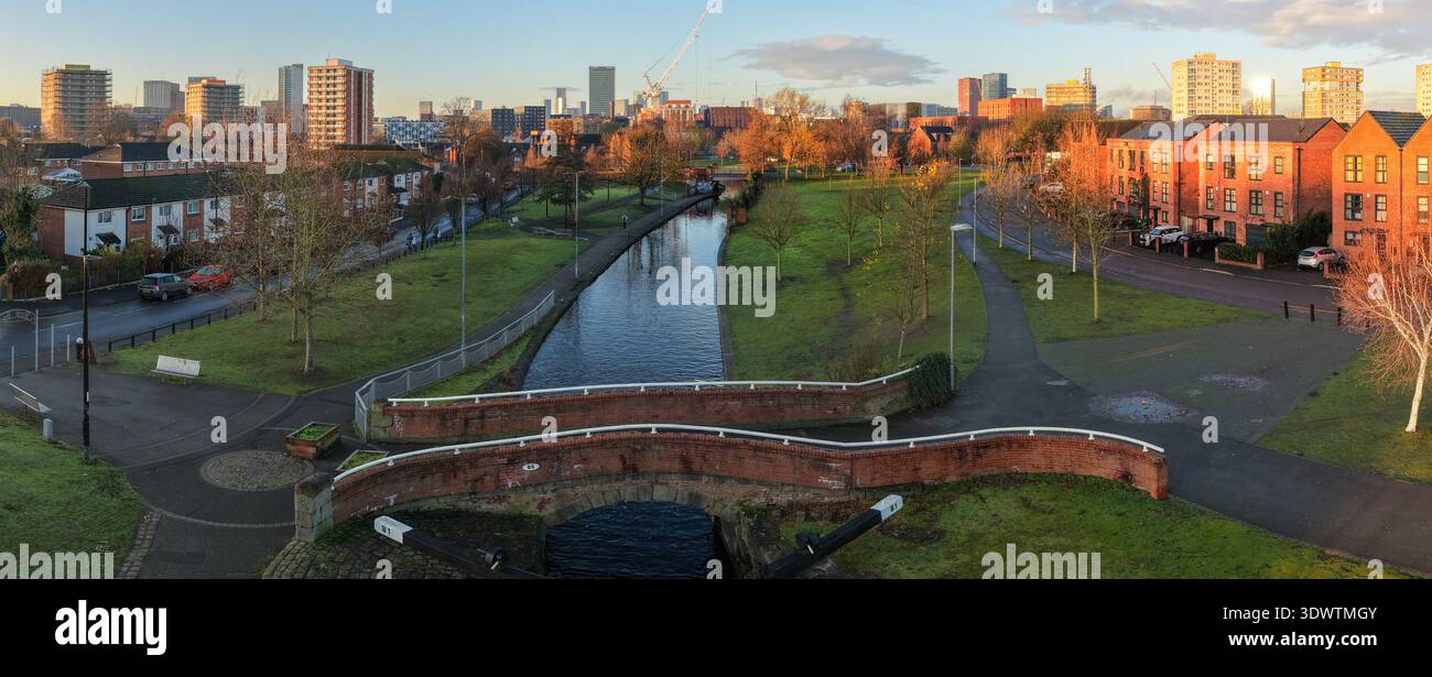 Immagine aerea del canale di Rochdale a Miles Platting all'alba, con lo storico Ponte 81, alloggi sostenibili e il lontano skyline di Manchester. Foto Stock