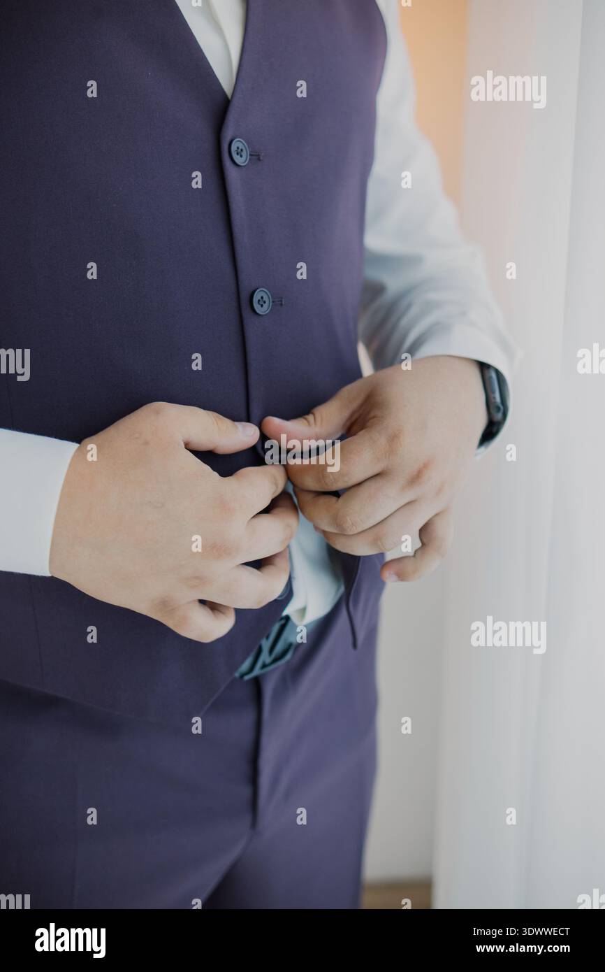 Un uomo che abbottonava il giubbotto vicino a una finestra Foto Stock