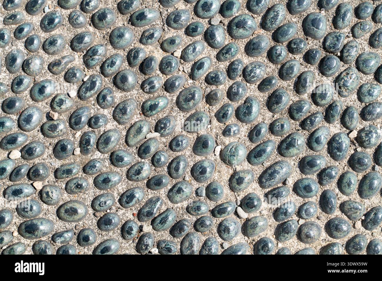 Passerella a mosaico di ciottoli naturali con pietre ovali scure disposte in motivi irregolari, ideale per il design del giardino e del patio. Foto Stock