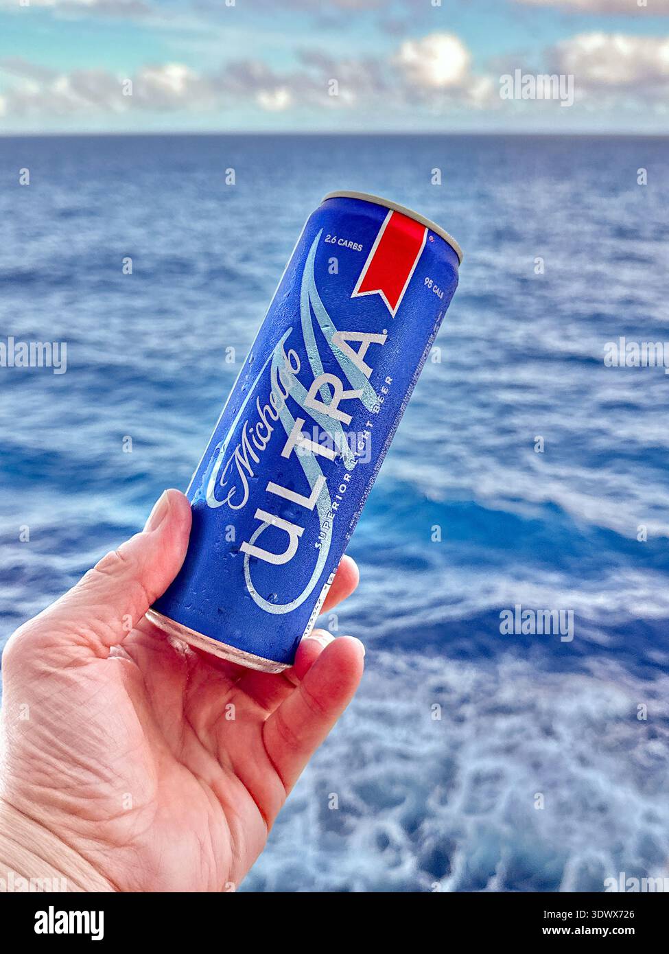 Tortola, Isole Vergini britanniche - 18 gennaio 2026: Persona in possesso di una lattina di birra fresca Michelob Ultra leggera sul lato del ponte di una nave da crociera - Immagine stock catturata con smartphone