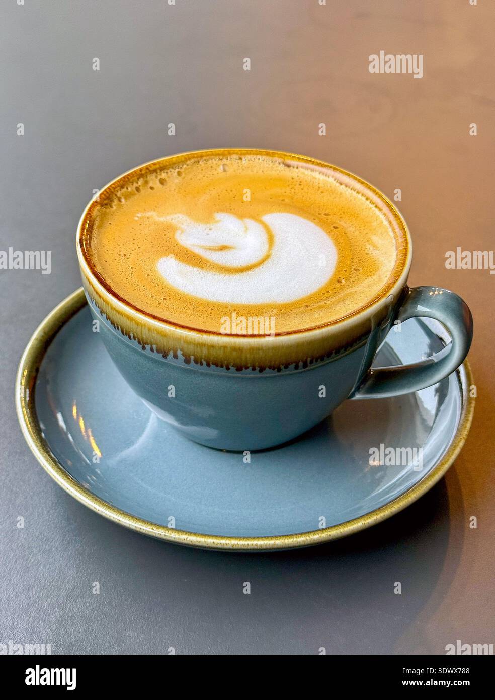Tazza di caffè caldo appena sgranato con piattino su un tavolo. Niente persone. Foto Stock