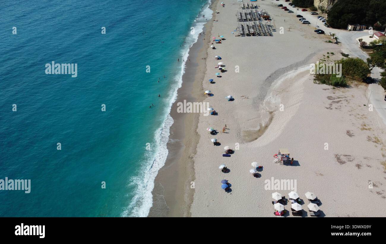 Ampia vista aerea della spiaggia di Karavostasi vicino a Perdika, Grecia. Ripresa da droni di lettini organizzati, costa sabbiosa e mare turchese dello Ionio da un angolo laterale. Foto Stock