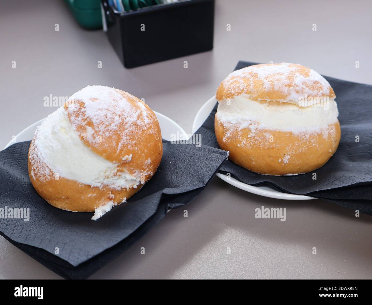 Tradizionale maritozzo italiano ripieno di panna montata fresca e spolverato con zucchero a velo, servito su un piatto. Classico dessert romano, dolce Foto Stock