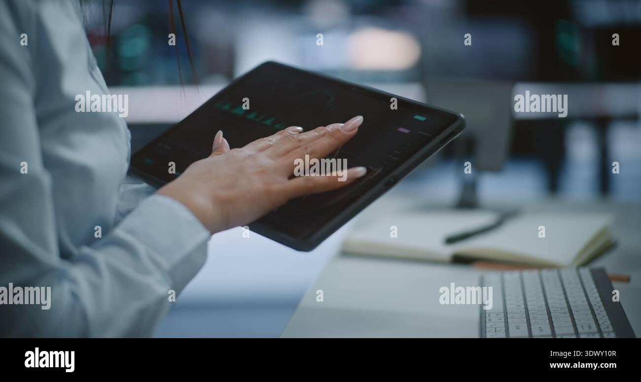 Primo piano di mani professionali che utilizzano il tablet per monitorare le tendenze del mercato azionario e le tabelle delle candele verdi. Concetto di Mobile Trading, Digital Asset Management e Real Time Financial Data Tracking. Foto Stock