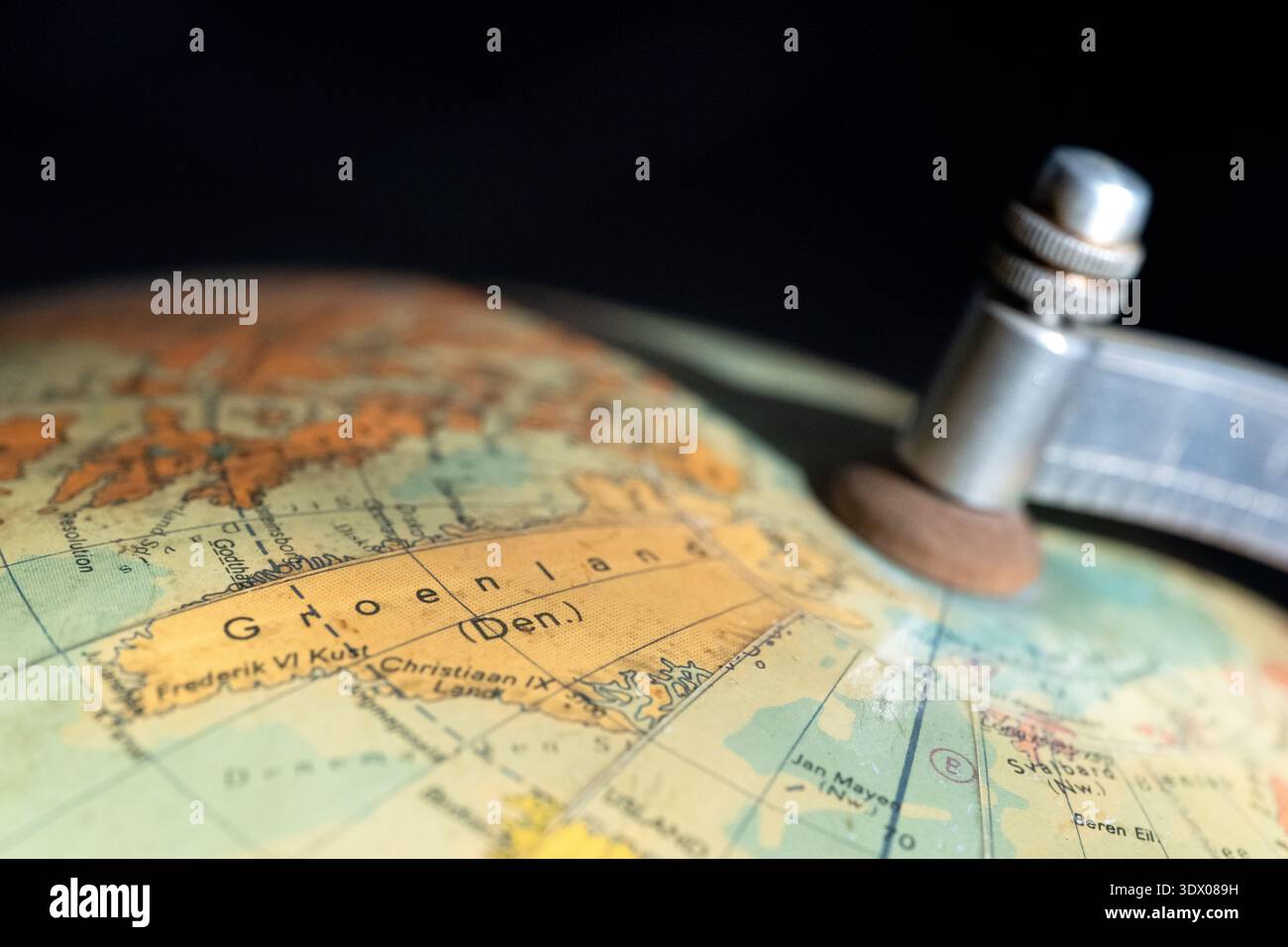 Globo mondiale d'epoca incentrato sulla Groenlandia (Groenlandia) e sul Circolo Polare Artico, che mostra dettagli topografici e un asse meridiano metallico. Foto Stock