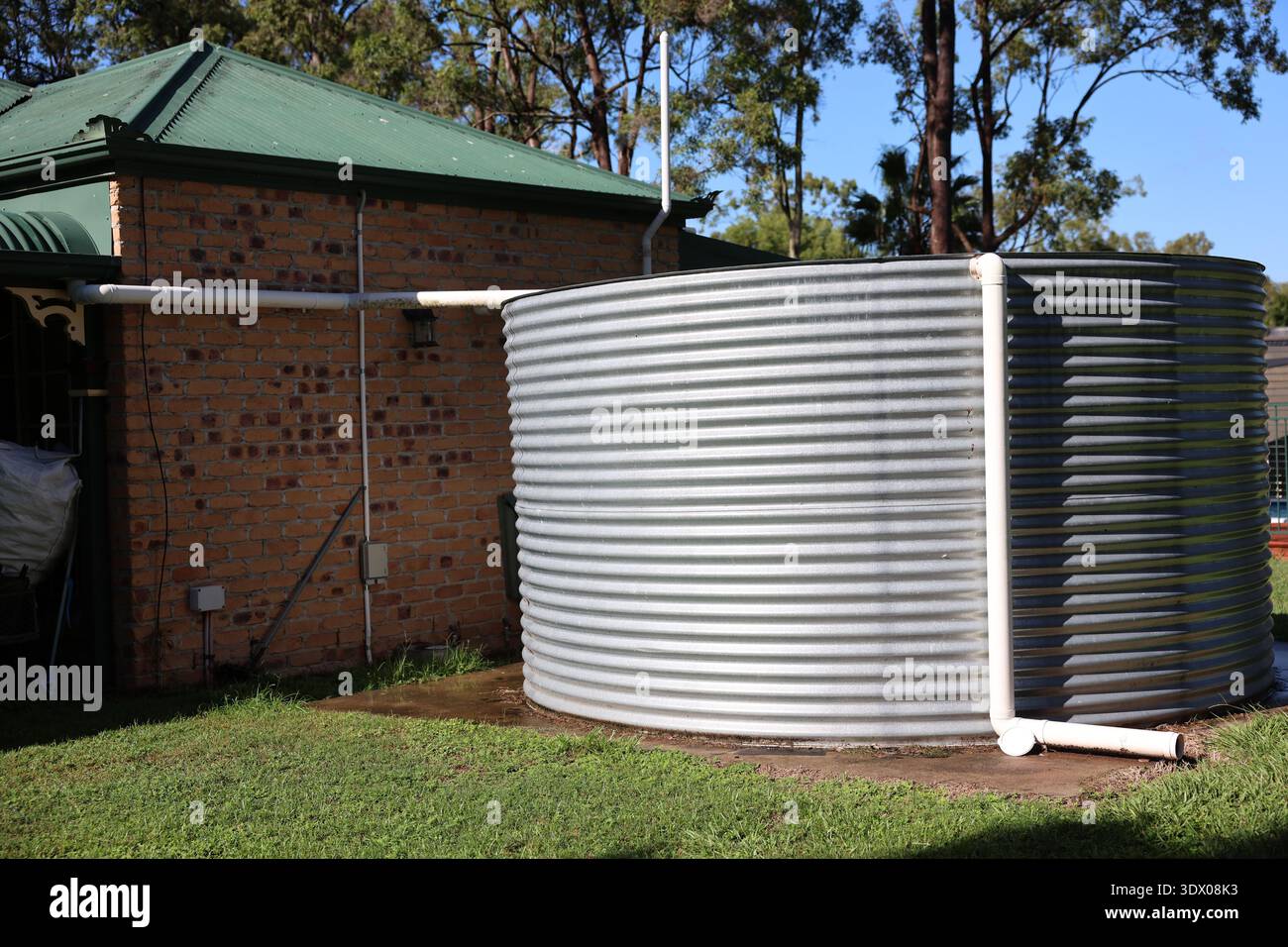 Grande serbatoio di acqua piovana in un cortile con erba e alberi in un ambiente periferico, Queensland, Australia. Foto Stock