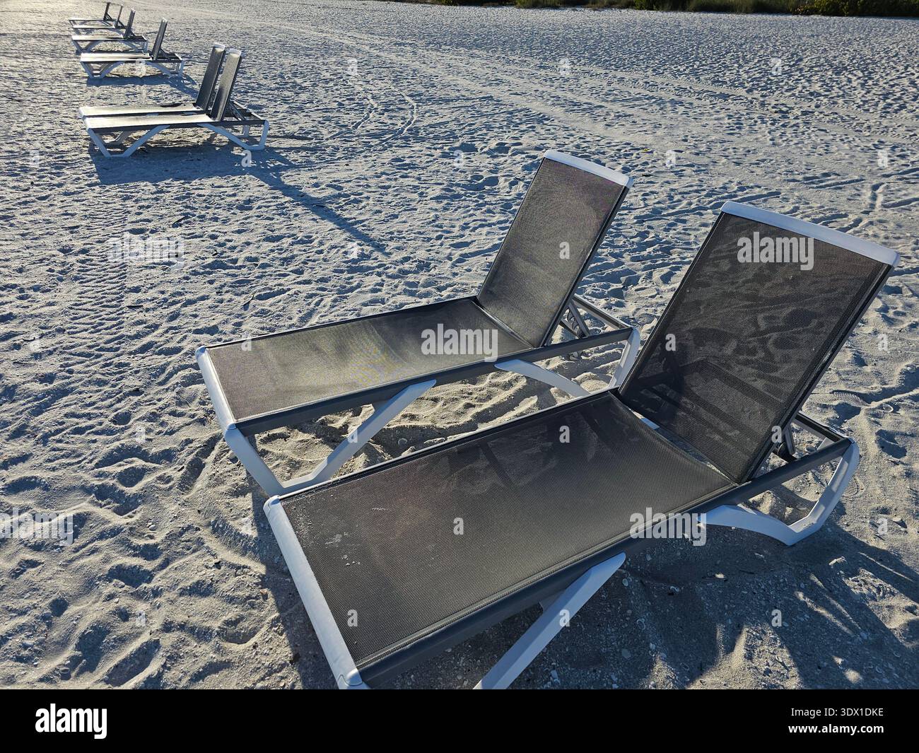 Lettini sdraiati sulla spiaggia allineati per una prospettiva sempre più snella Foto Stock