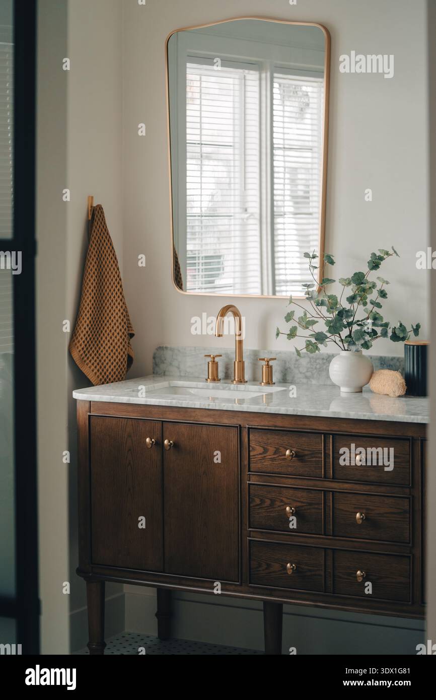 Moderno lavandino del bagno con rubinetto in ottone e ripiano in marmo in luminosi interni di casa. Foto Stock
