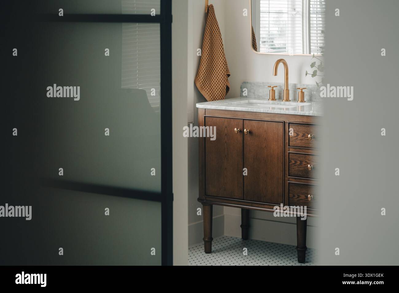 Moderno lavandino del bagno con rubinetto in ottone e ripiano in marmo in luminosi interni di casa. Foto Stock