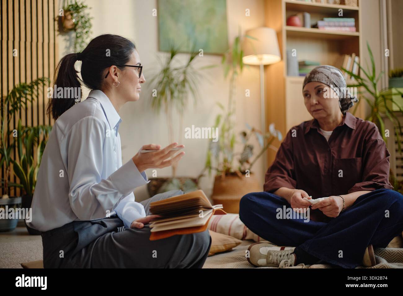 Donna caucasica di mezza età che coinvolge una donna anziana in una conversazione di supporto in casa Foto Stock