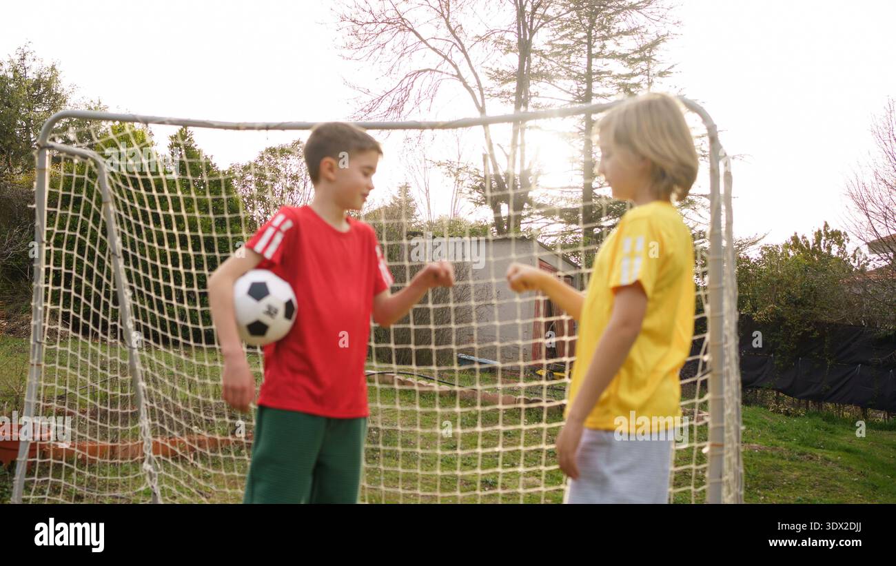 Due ragazzi che battono il pugno dopo aver giocato a calcio su un campo erboso Foto Stock