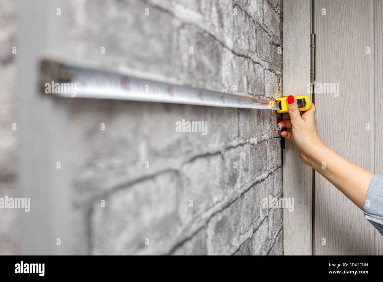 una donna misura un muro con un metro. un metro a nastro nelle mani di una donna. gancio per roulette. Foto Stock