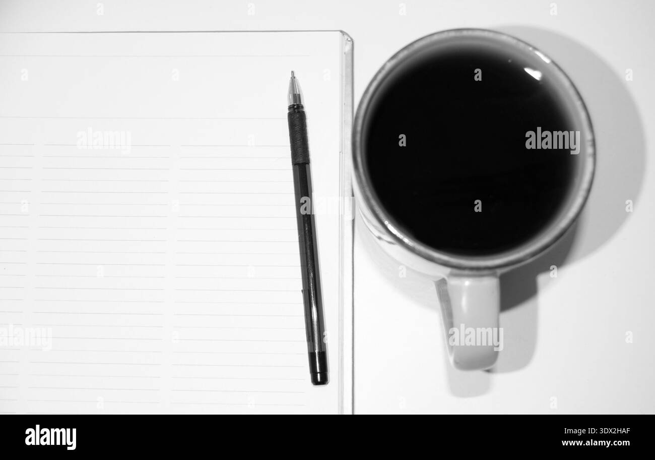 Una penna, un taccuino e una tazza di tè o caffè nero. Quadro di pianificazione con spazio di copia. Una cornice in bianco e nero con una penna e un notebook. Foto Stock