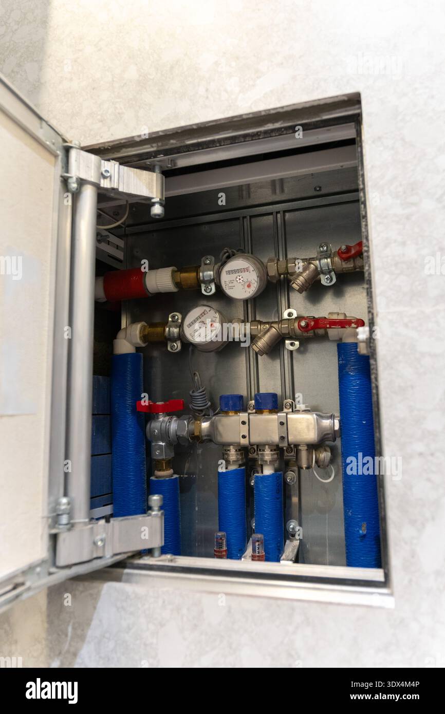 Misuratori d'acqua, installazione di tubi all'interno di un armadio a parete, sistema idraulico residenziale con indicatori, valvole e tubi blu rossi, gestione delle utenze e. Foto Stock
