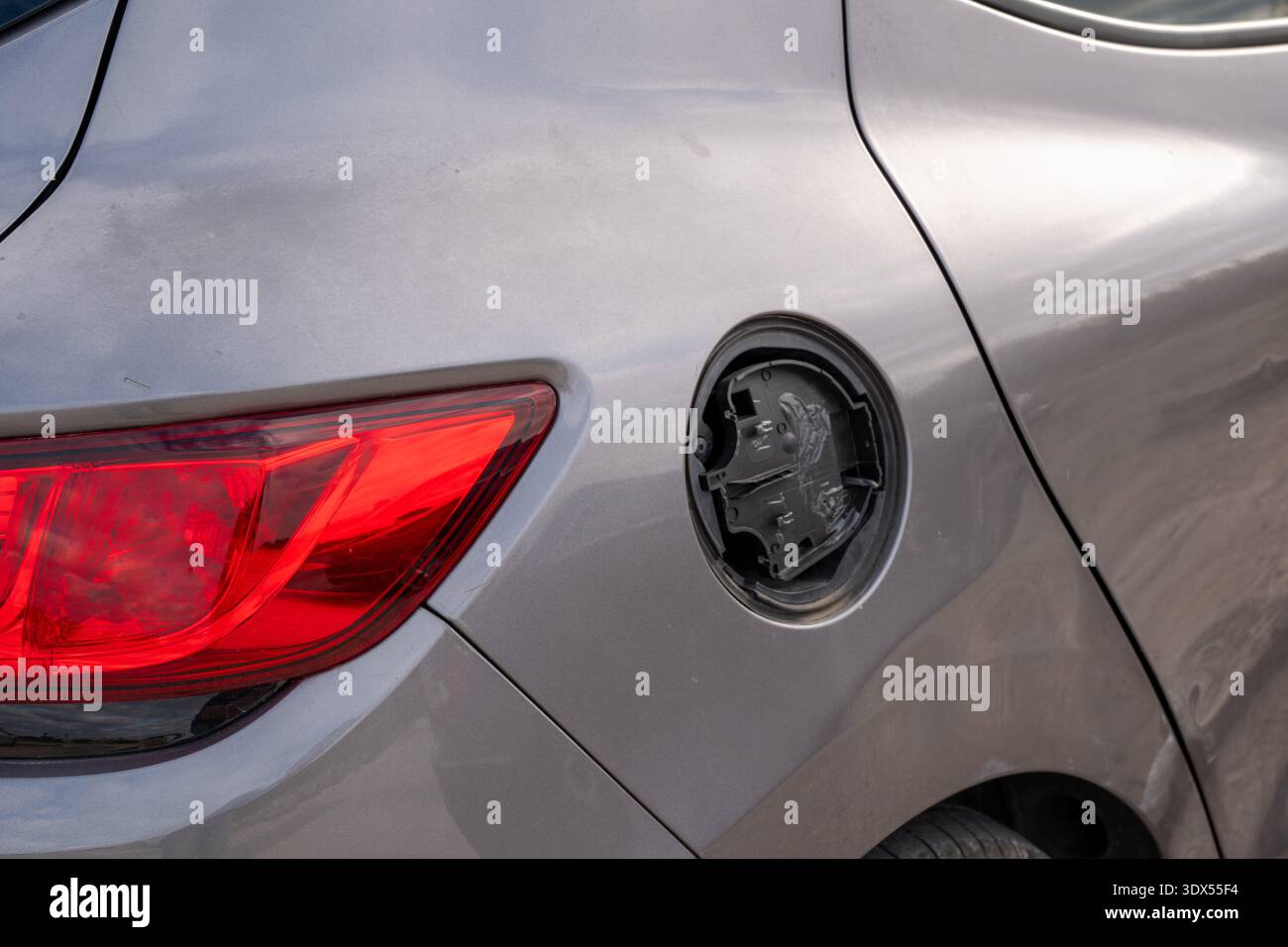 Vista posteriore di un'auto grigia che mostra un coperchio dello sportello del serbatoio del carburante mancante o rotto Foto Stock