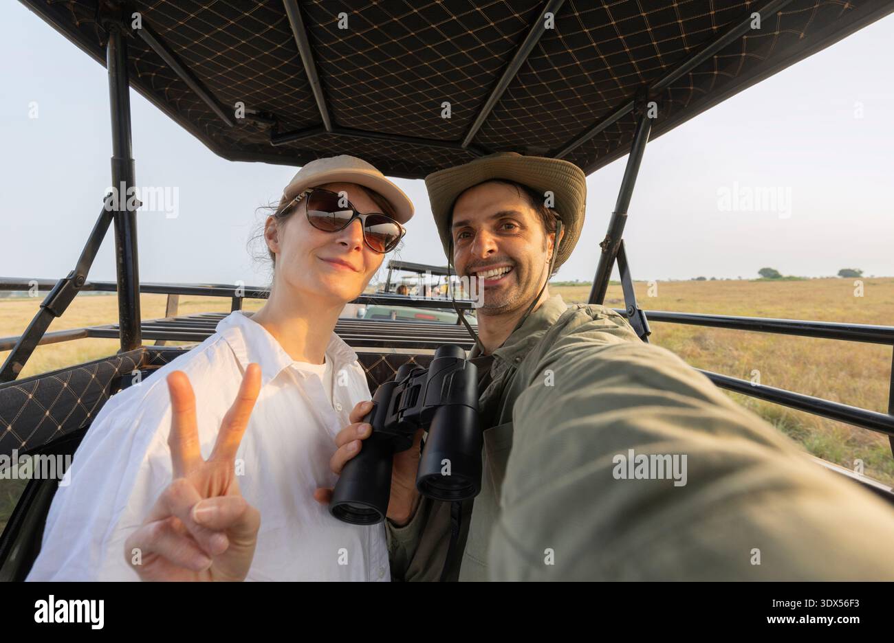 Un uomo e una donna sono seduti in un'auto fuoristrada. L'uomo indossa una felpa con cappuccio verde durante il safari nel parco in Sud Africa Foto Stock