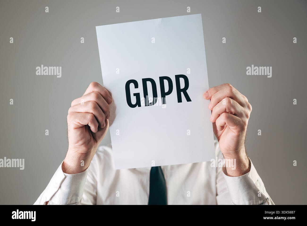 Un uomo d'affari con in mano un cartello bianco con il testo nero in grassetto del GDPR davanti al viso, che oscura l'identità per la protezione dei dati e la legge sulla privacy, complimenti Foto Stock