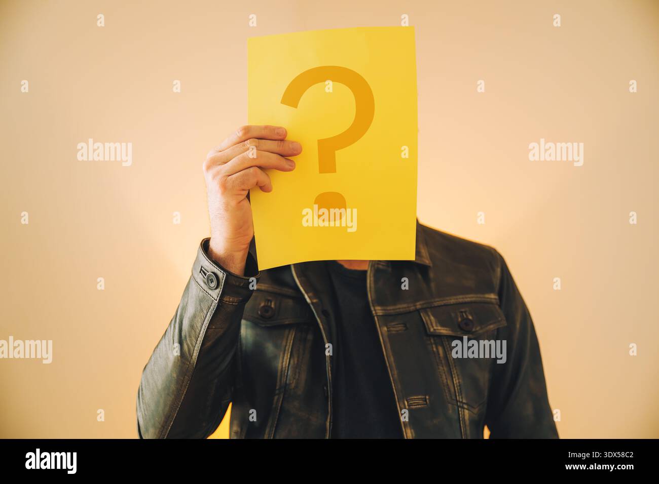 Uomo con un punto interrogativo giallo che copre il viso, misterioso ritratto a fuoco selettivo Foto Stock