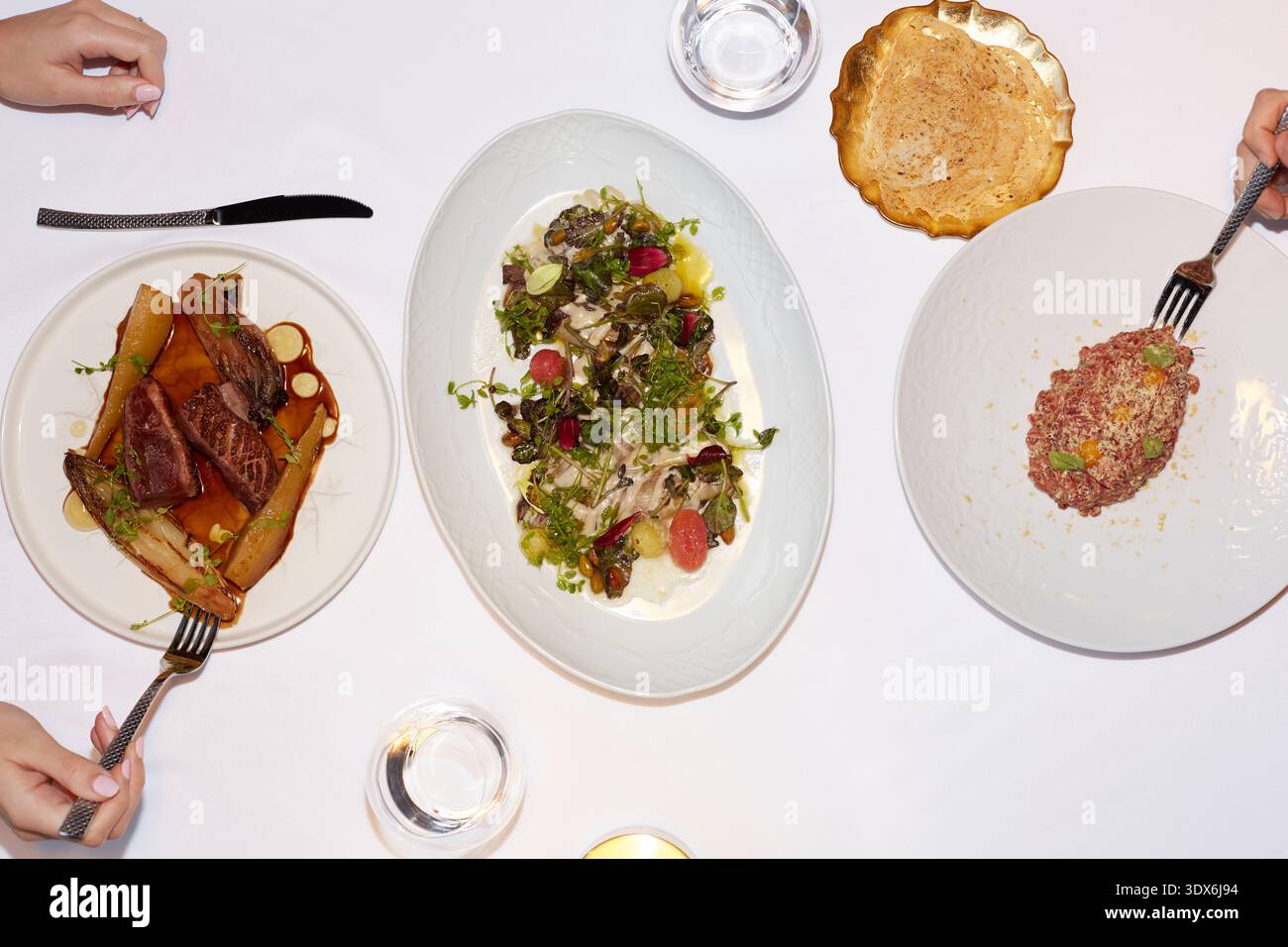 Una gamma di piatti gourmet presentati elegantemente su un'immacolata tovaglia bianca in un raffinato ristorante, che mostra squisita arte culinaria e. Foto Stock