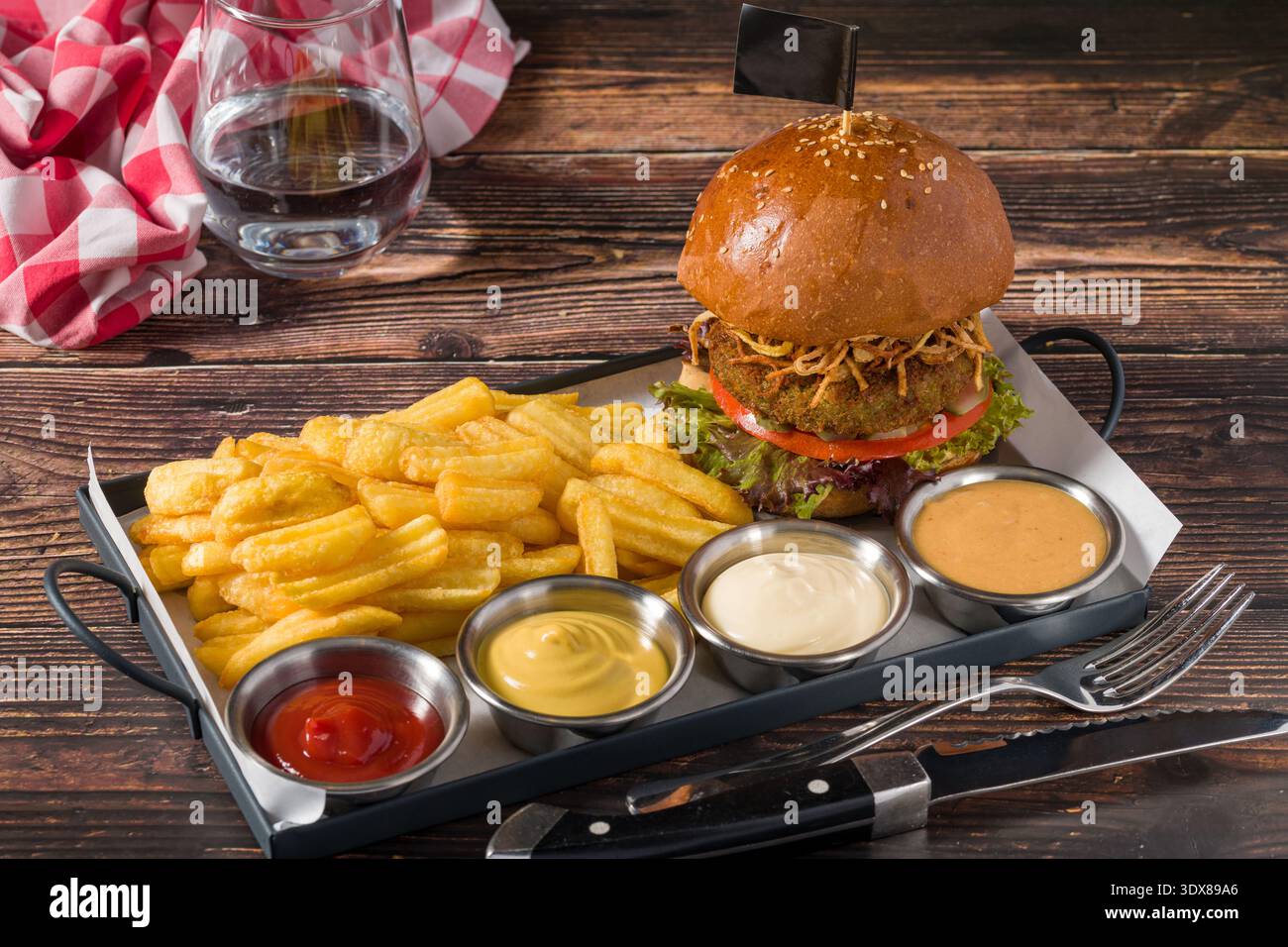 Hamburger vegano servito con patatine fritte e salse Foto Stock