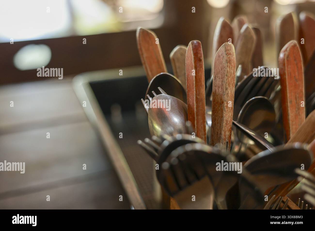 Collezione calda e rustica di posate in legno vintage. Cucchiai e forchette, un assortimento di posate e utensili in cucina per creare un ambiente accogliente, Foto Stock