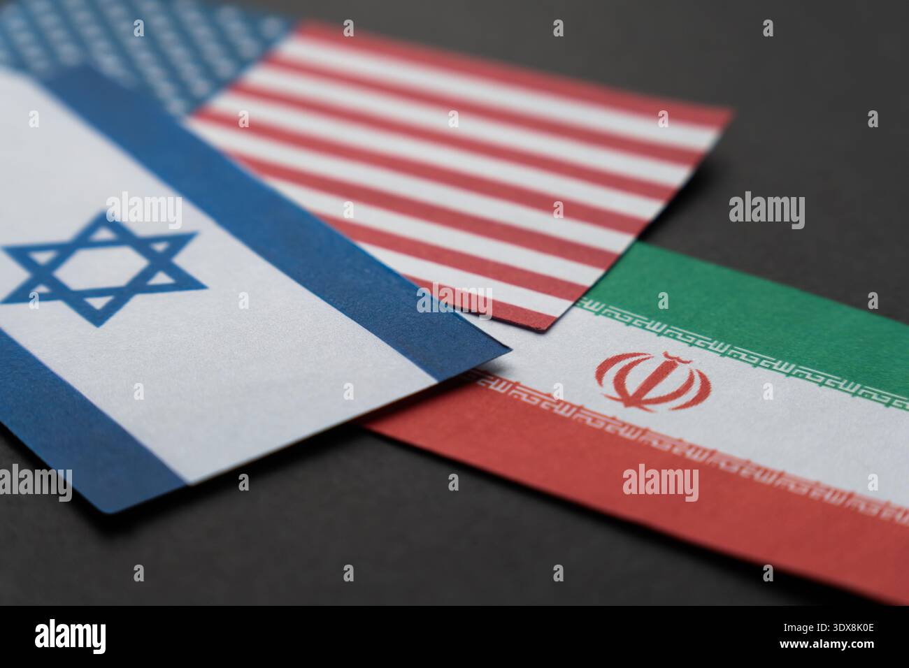 Le bandiere di Israele, Stati Uniti e Iran si sovrappongono su una superficie scura. Tensioni militari tripartite, guerra regionale in Medio Oriente e geopolitica Foto Stock