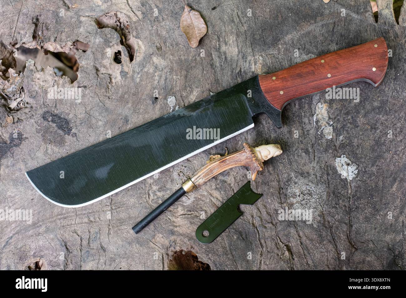 Un coltello a macchete e un'asta per accendere il fuoco giacciono sul pavimento di legno Foto Stock