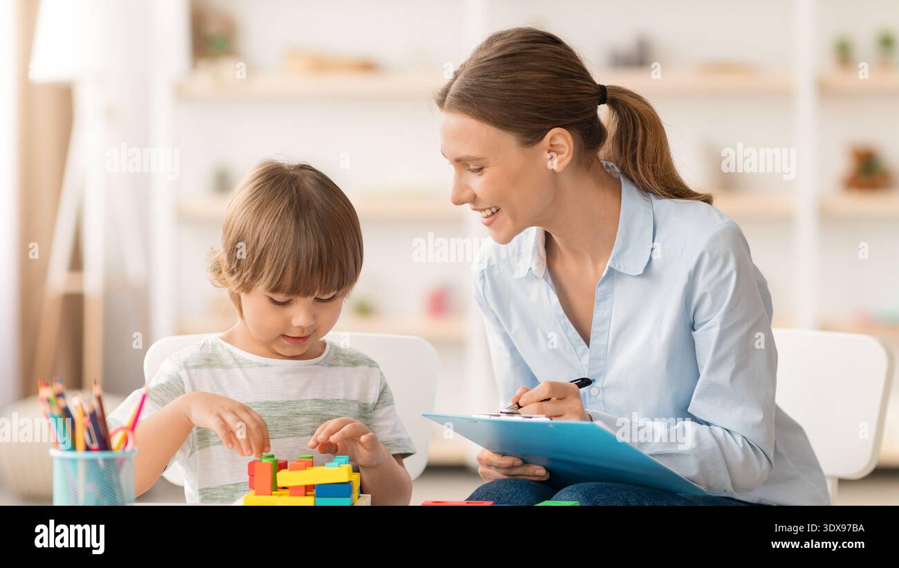 Bambini e adulti costruiscono con blocchi colorati in una sala giochi durante una divertente attività didattica Foto Stock