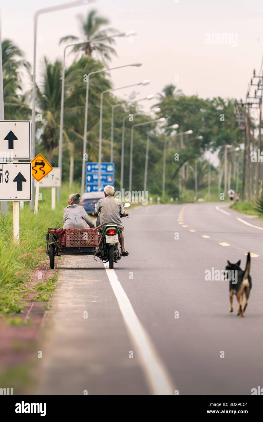 Momenti autentici della vita rurale quotidiana della Thailandia meridionale, che si possono vedere viaggiando attraverso il Sud-Est Asiatico: Una coppia di anziani corre a m Foto Stock