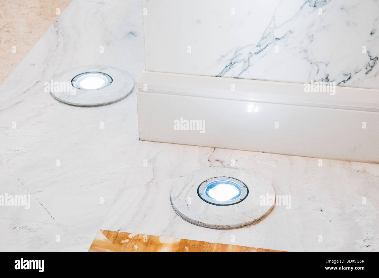 Faretti da incasso che forniscono un'illuminazione d'accento su un elegante pavimento in marmo, valorizzando il moderno design degli interni e gli elementi architettonici Foto Stock