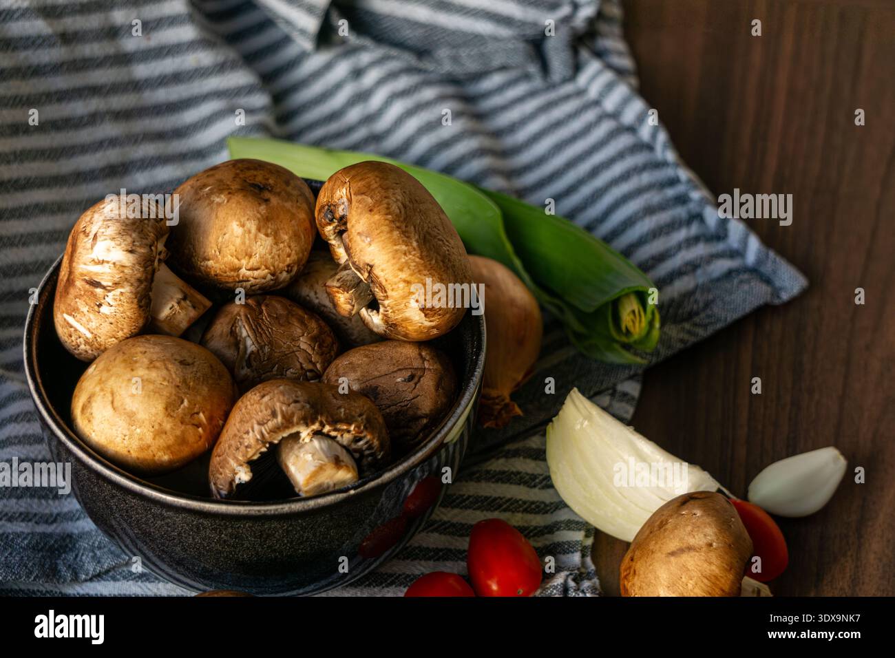 Champignon marroni freschi disposti in una ciotola di ceramica su un tavolo di legno. Foto Stock
