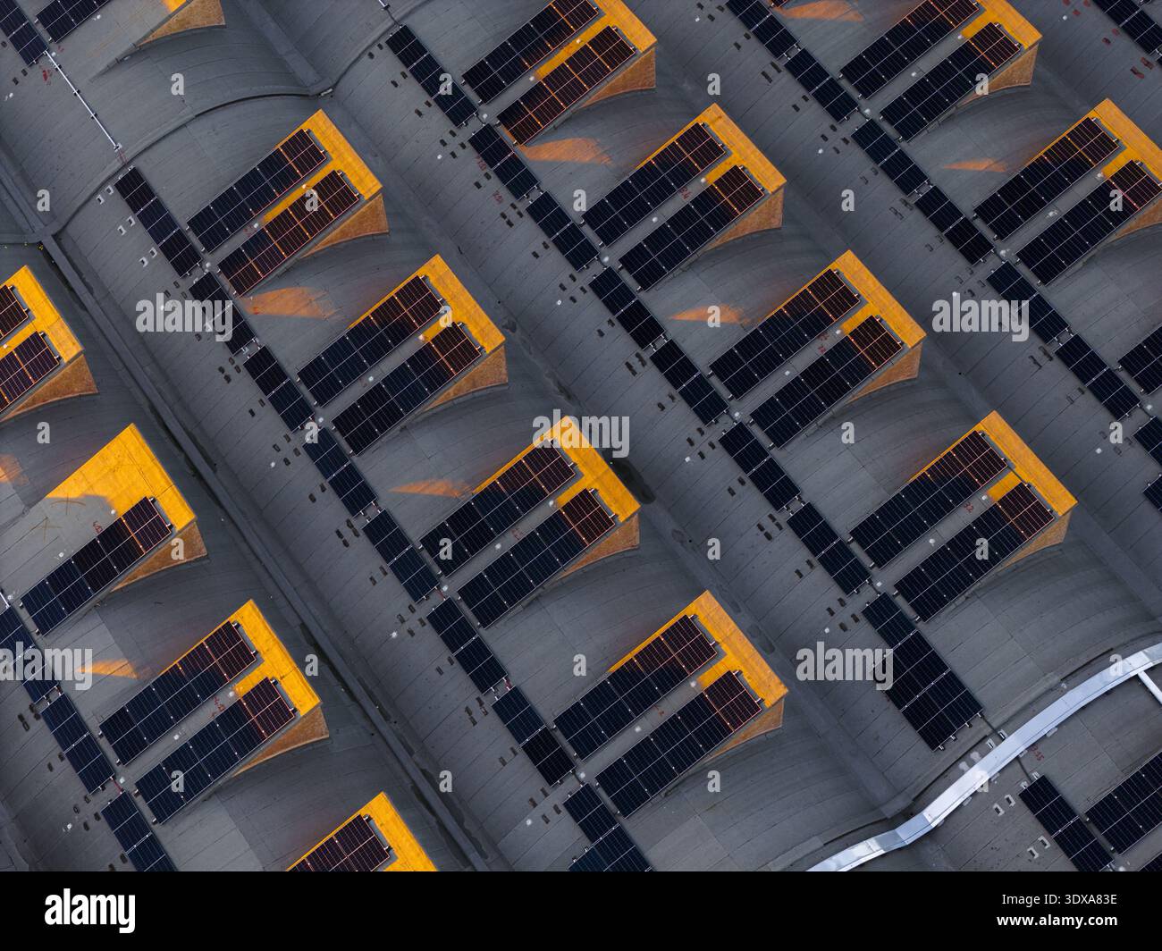 Veduta aerea del tetto di un edificio adornato con pannelli solari e strutture gialle, che creano uno schema geometrico di luce e ombra, Roma, Lazio, Italia. Foto Stock