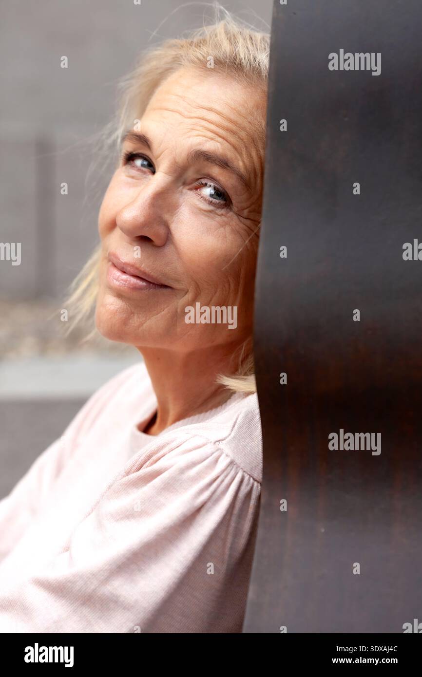 Ritratto di una donna anziana appoggiata al muro Foto Stock