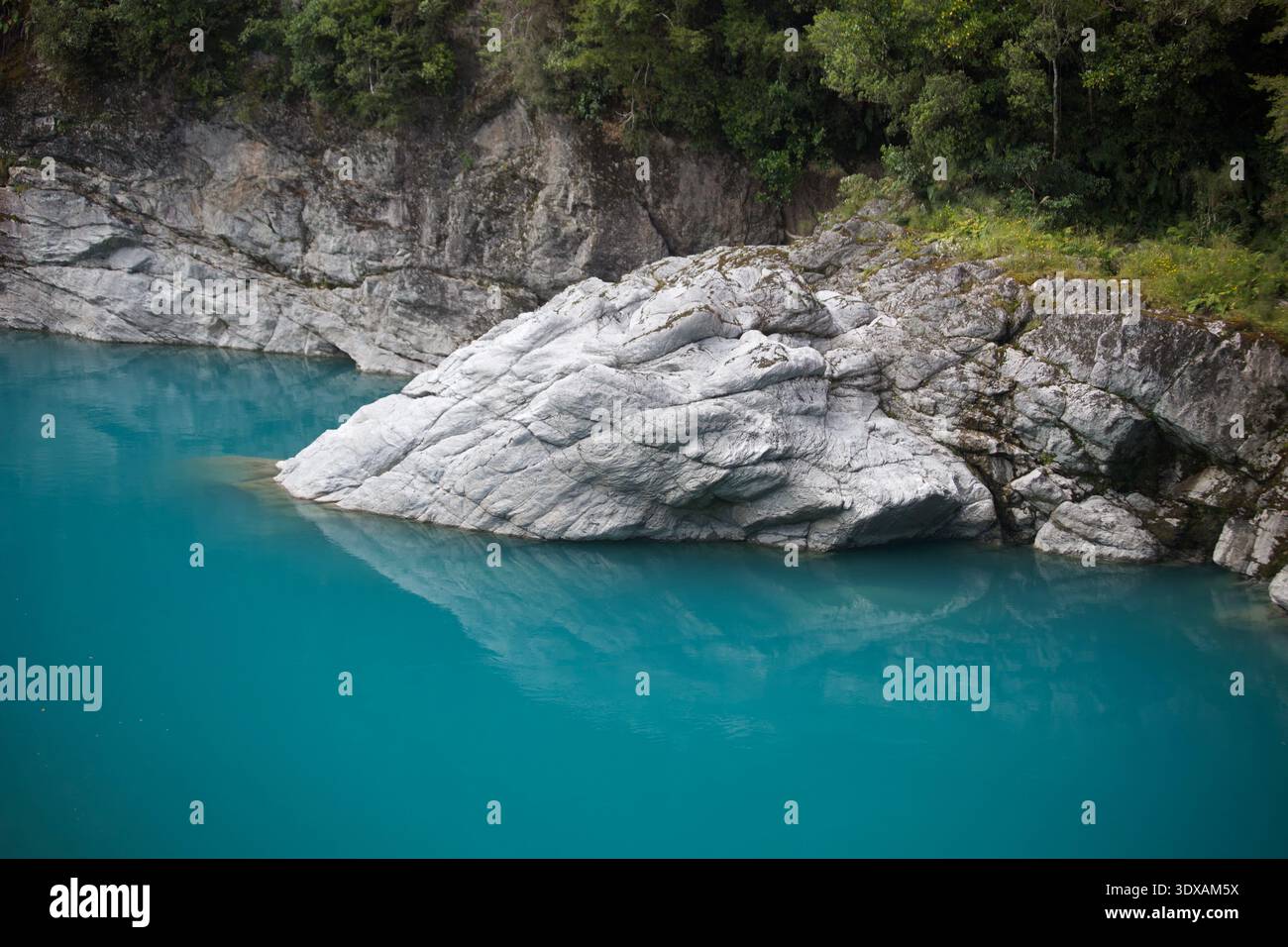 Formazione rocciosa grigia intemprata che emerge dalle vivide acque turchesi glaciali di Hokitika Gorge, West Coast, South Island, nuova Zelanda Foto Stock