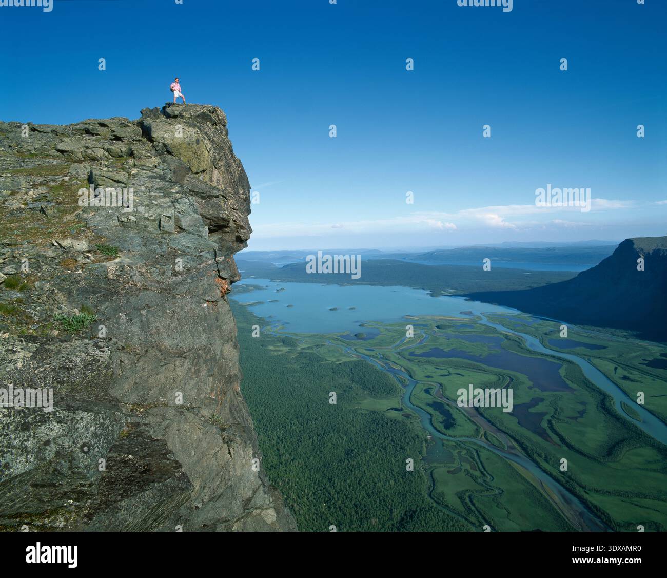 Vista distante dell'uomo in piedi sul bordo di una scogliera rocciosa contro il cielo Foto Stock