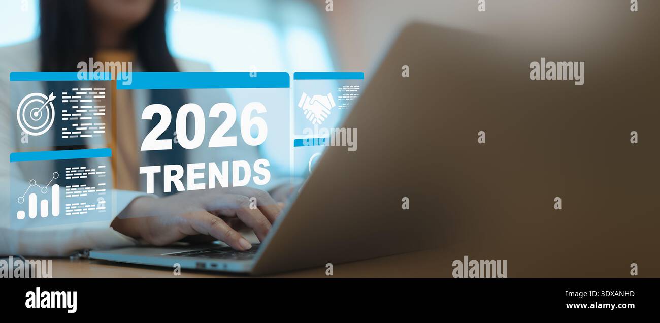 Donna d'affari che utilizza un notebook per analizzare le tendenze del 2026 con un'interfaccia digitale virtuale che mostra in modo moderno obiettivi aziendali, grafici di dati e icone di partnership Foto Stock