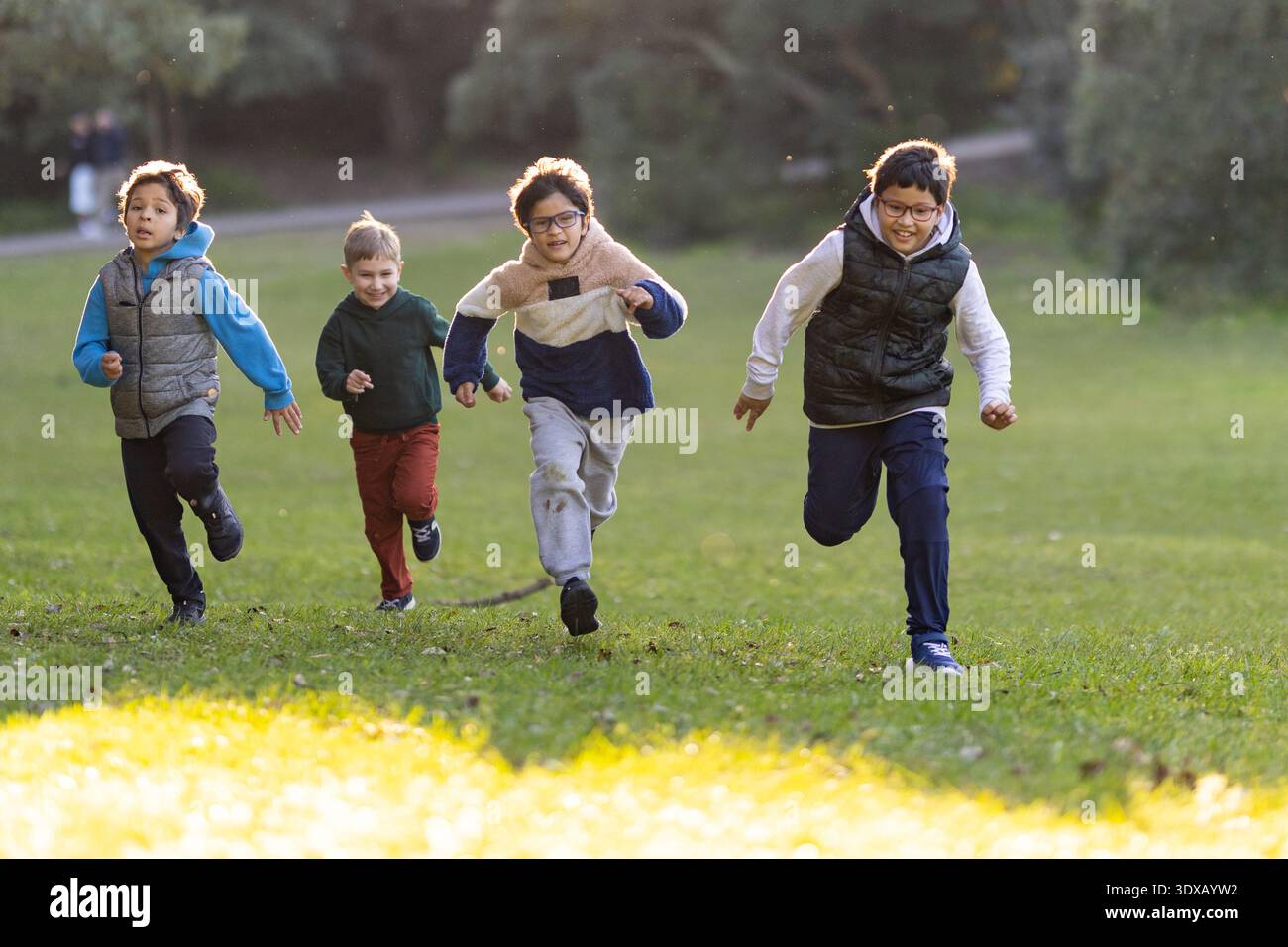 Quattro ragazzi felici che corrono a giocare nel parco Foto Stock
