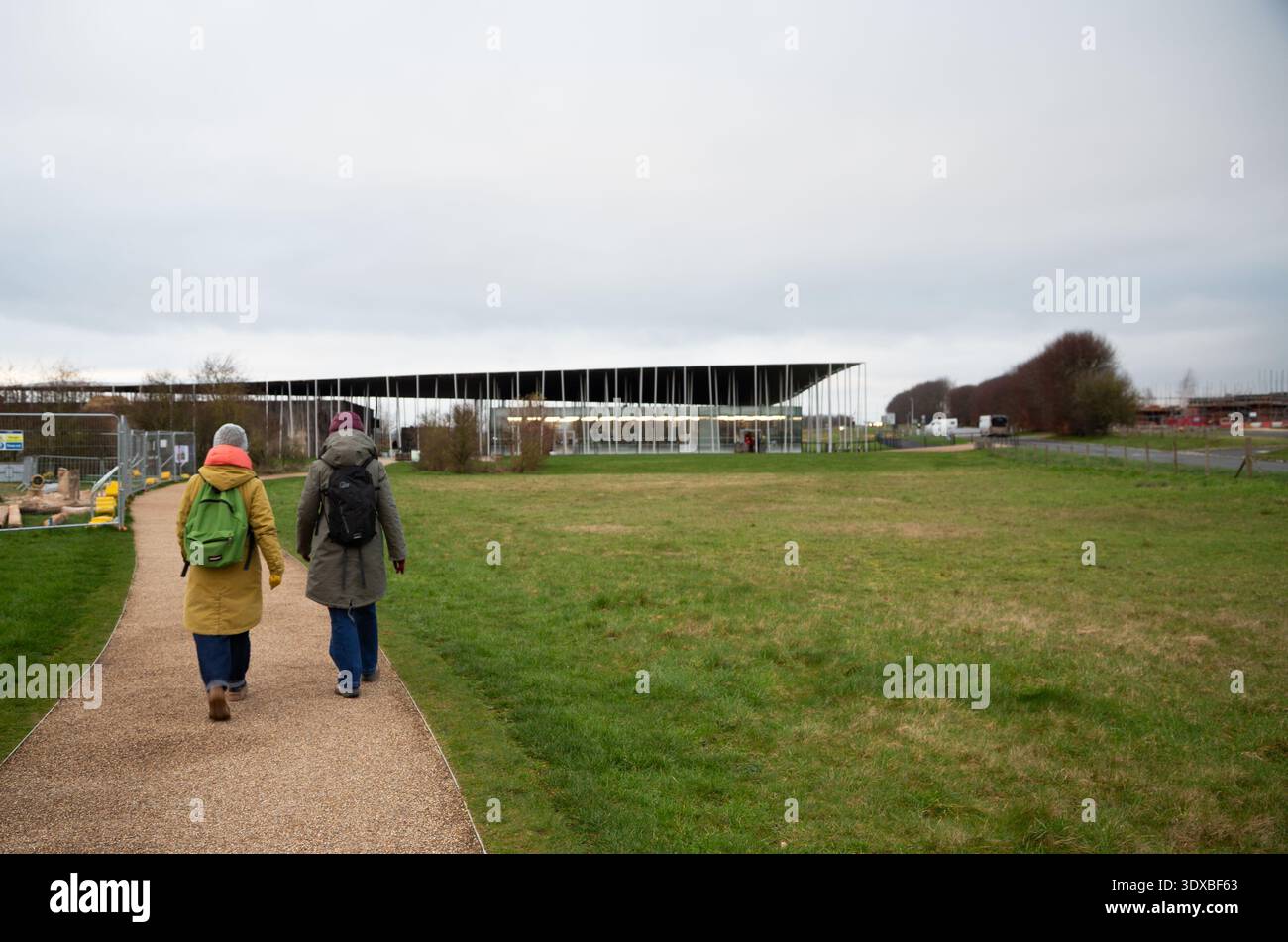 Due donne in inverno vestiti da trekking camminano verso Stonehenge Visitor Centre, Salisbury, Wiltshire, Inghilterra Regno Unito Foto Stock