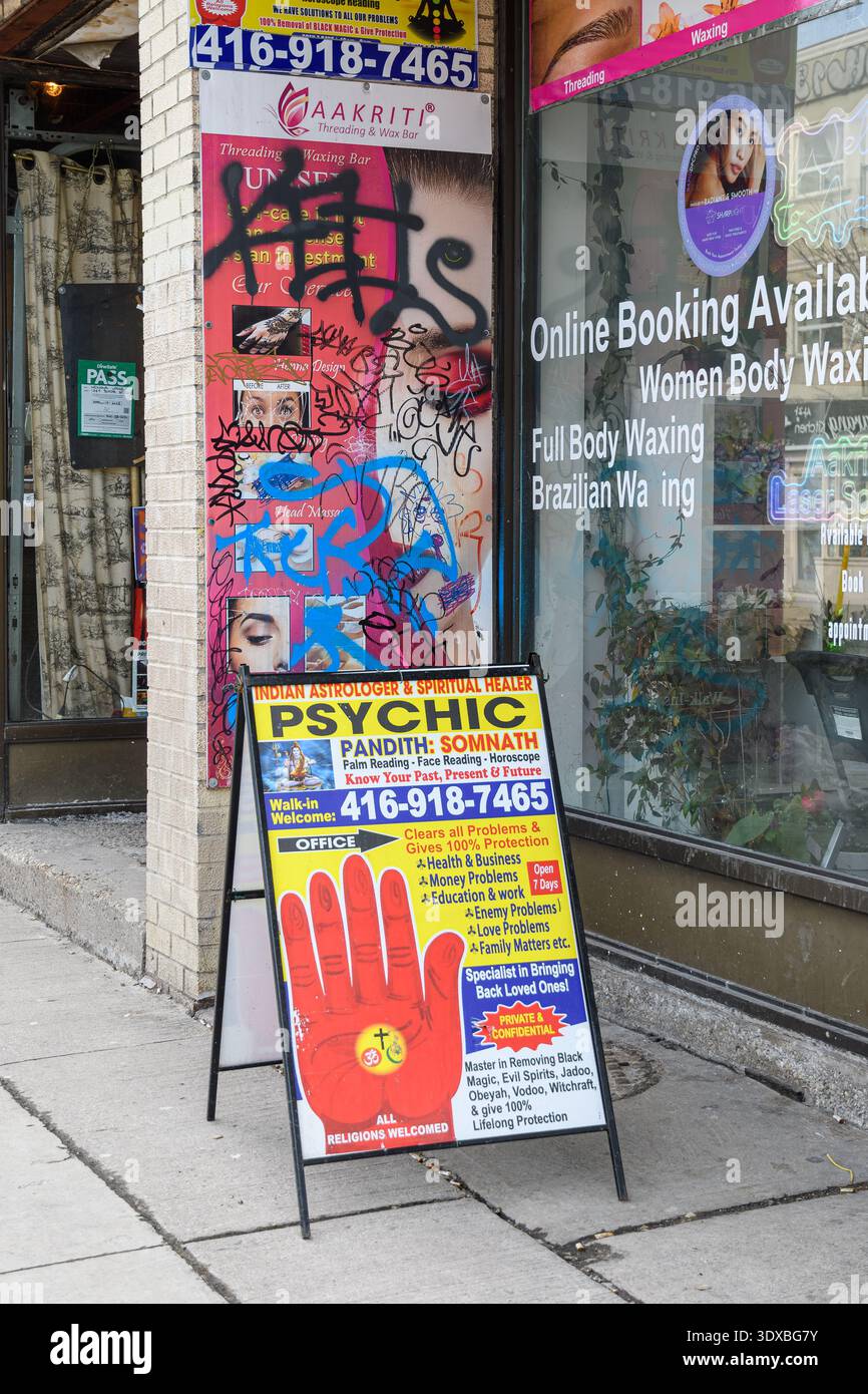Vetrina sul marciapiede con cartellone psichico, poster di graffiti, vetrina del salone, pubblicità di prenotazione e esposizione di numeri di telefono. Foto Stock