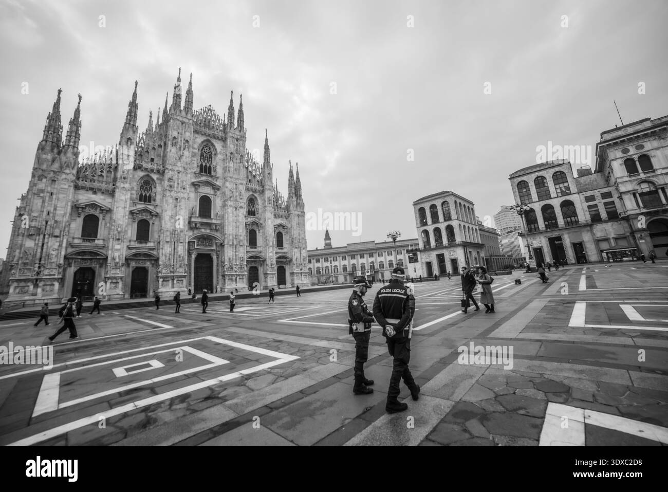 Milano Italia 27 febbraio 2026: Due poliziotti locali osservano la piazza di fronte al Duomo di Milano mentre un ciclista attraversa lo spazio urbano su una cl Foto Stock
