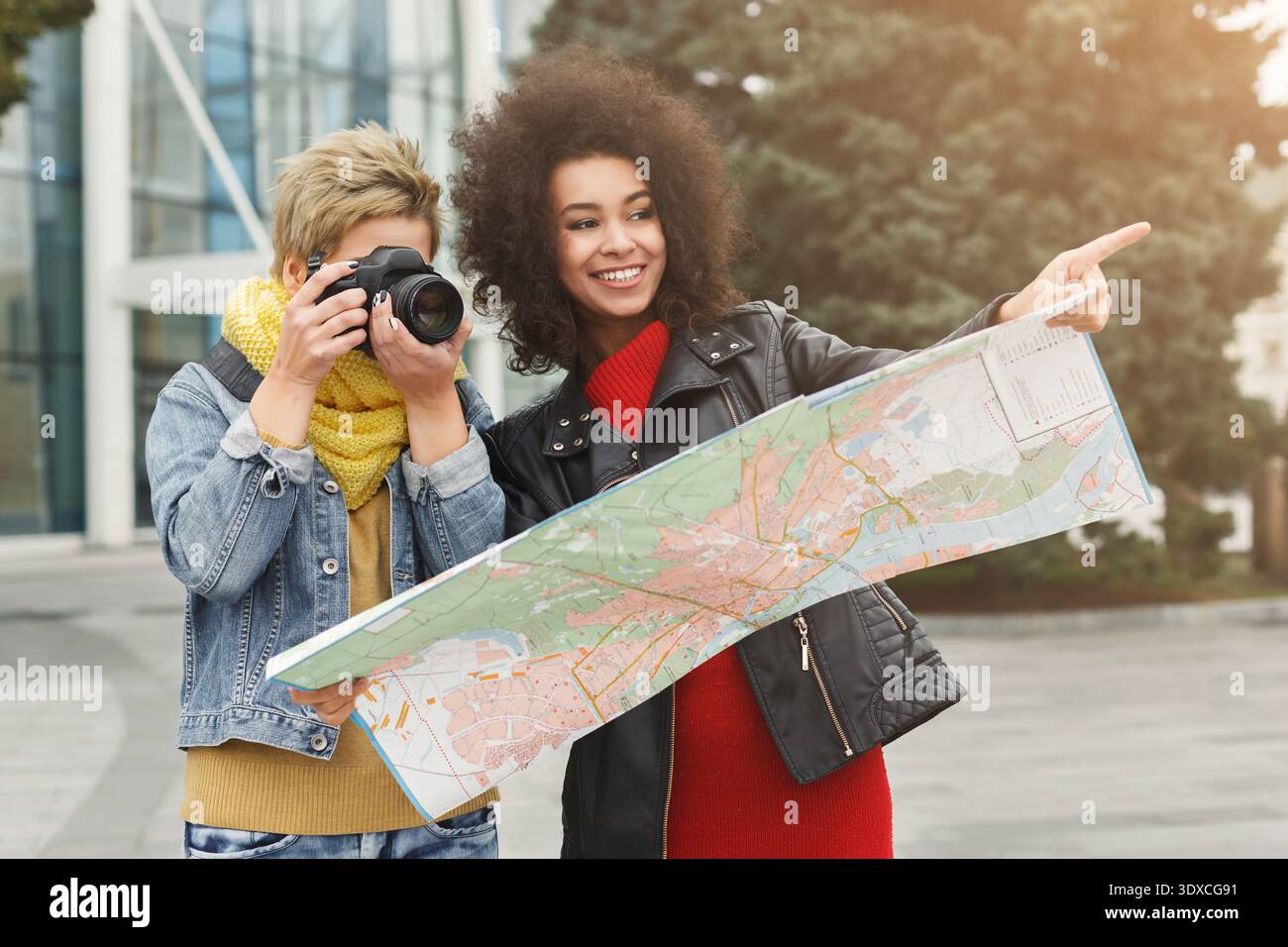 Due amici che si godono una giornata di esplorazione con una mappa e una fotocamera in un ambiente urbano Foto Stock