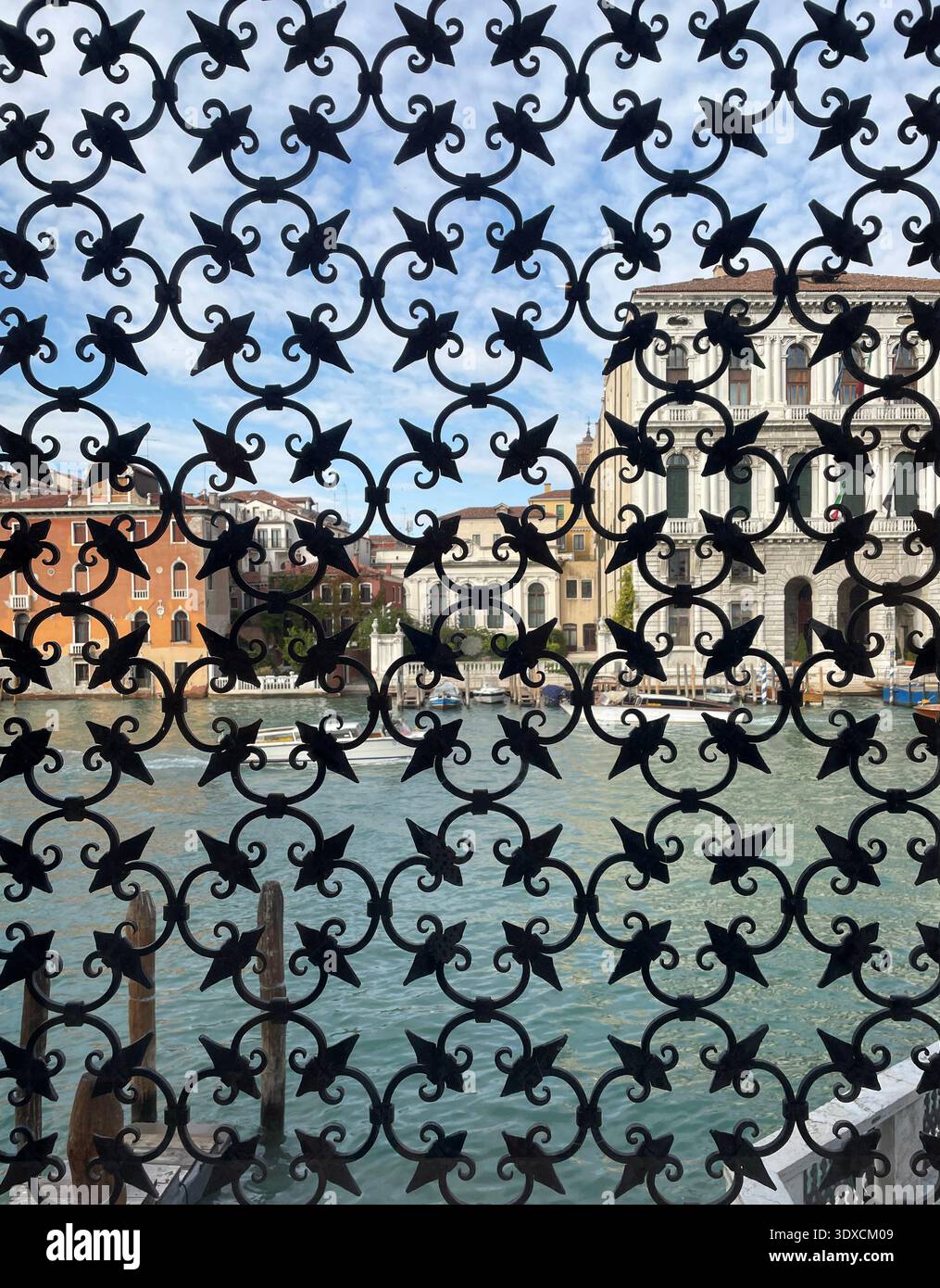 Decorato motivo a reticolo in ferro battuto che incornicia una vista sul Canal grande e sugli edifici storici di Venezia, Italia. - Immagine stock catturata con smartphone