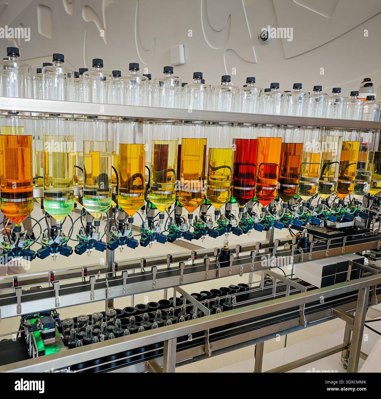 Produzione di profumi. Profumi diversi in bottiglia. Linea di produzione robotizzata di profumi con erogazione automatica di fragranze Foto Stock