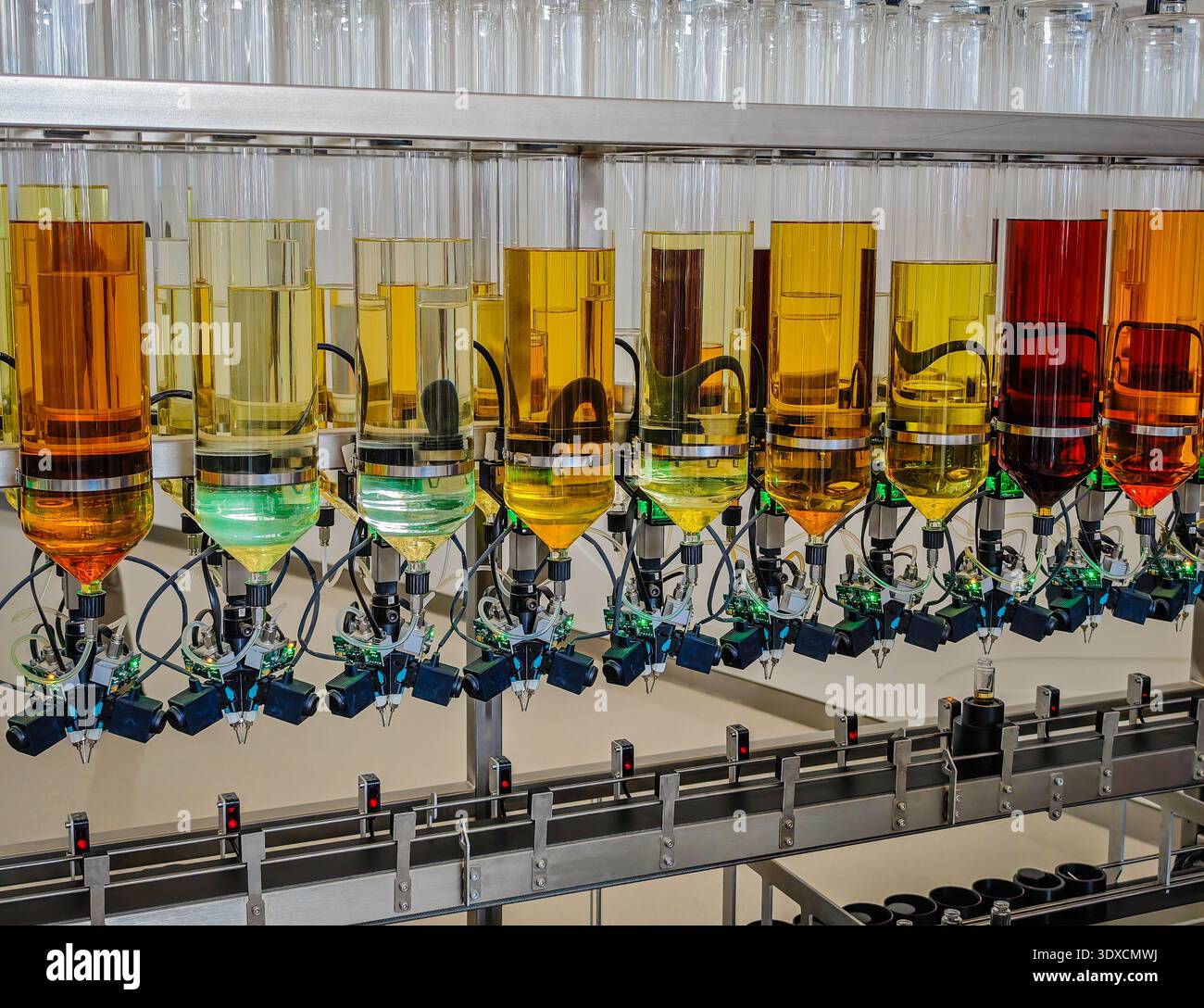 Produzione di profumi. Profumi diversi in bottiglia. Linea di produzione robotizzata di profumi con erogazione automatica di fragranze Foto Stock