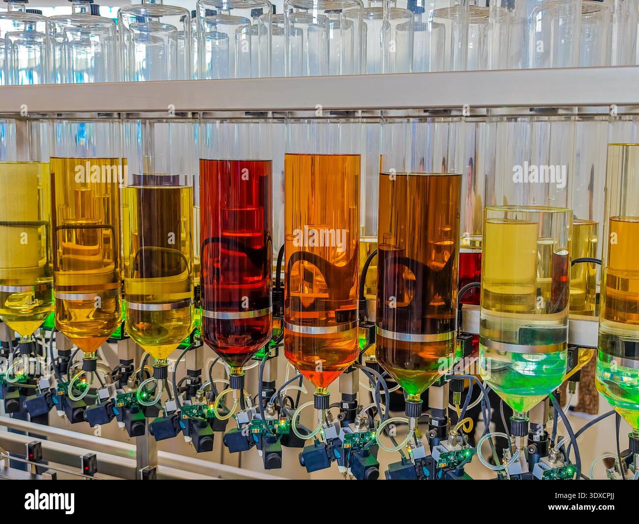 Produzione di profumi. Profumi diversi in bottiglia. Linea di produzione robotizzata di profumi con erogazione automatica di fragranze Foto Stock