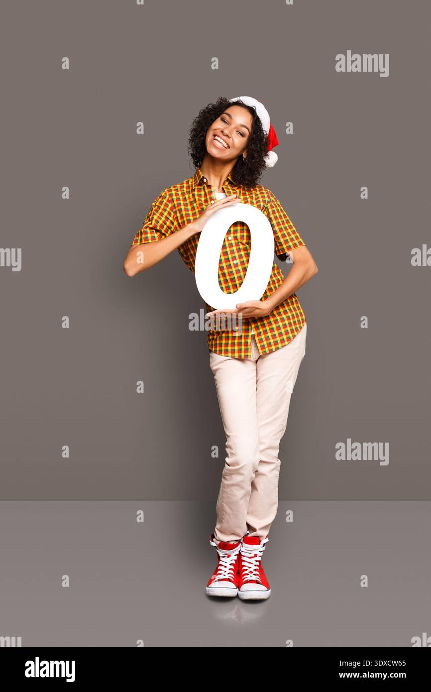 La persona che indossa il cappello di Natale tiene una lettera grande in una collezione di disegni per le feste Foto Stock