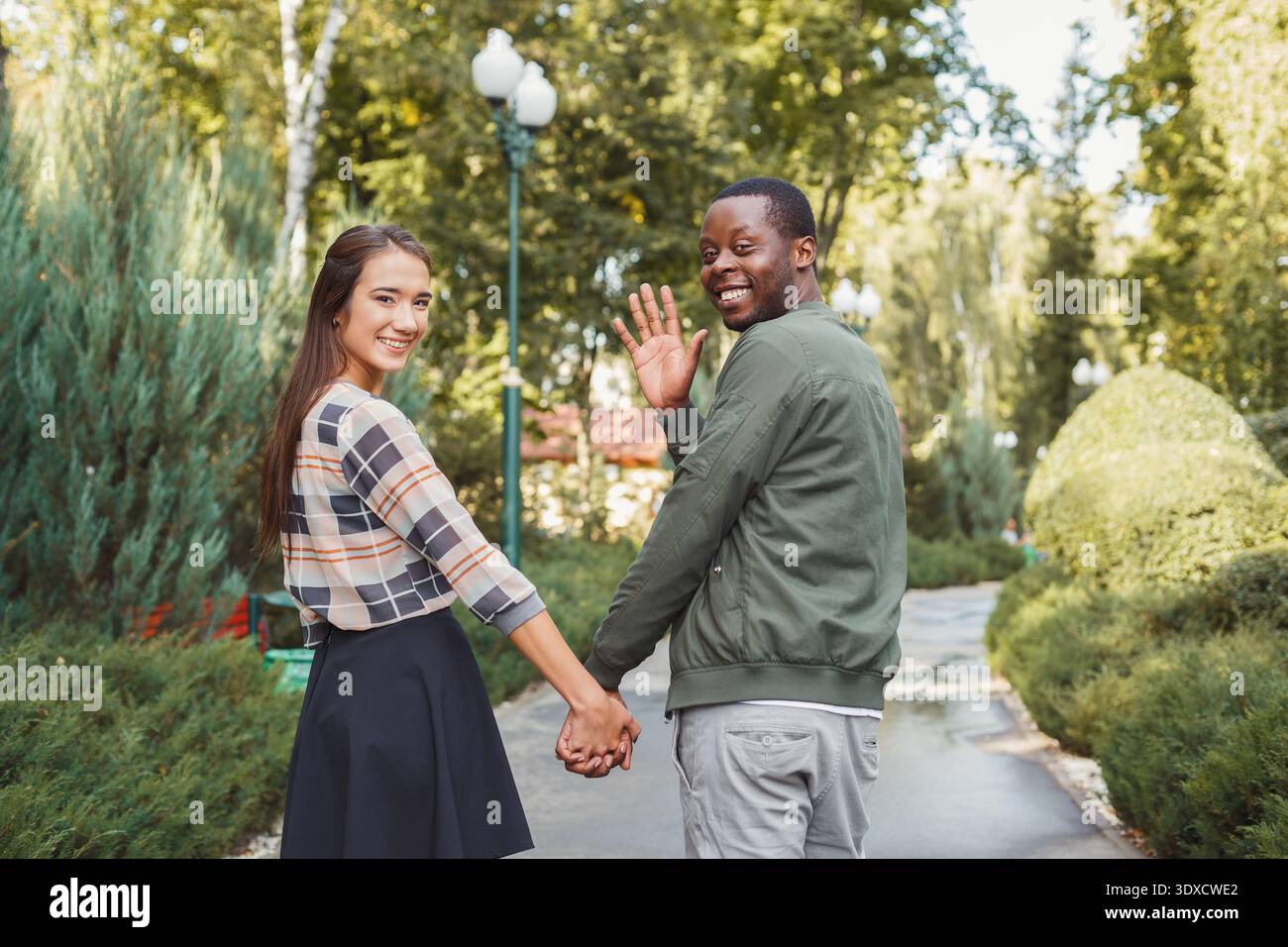 La coppia ama passeggiare in un parco tenendosi per mano e sorridendo davanti alla telecamera Foto Stock