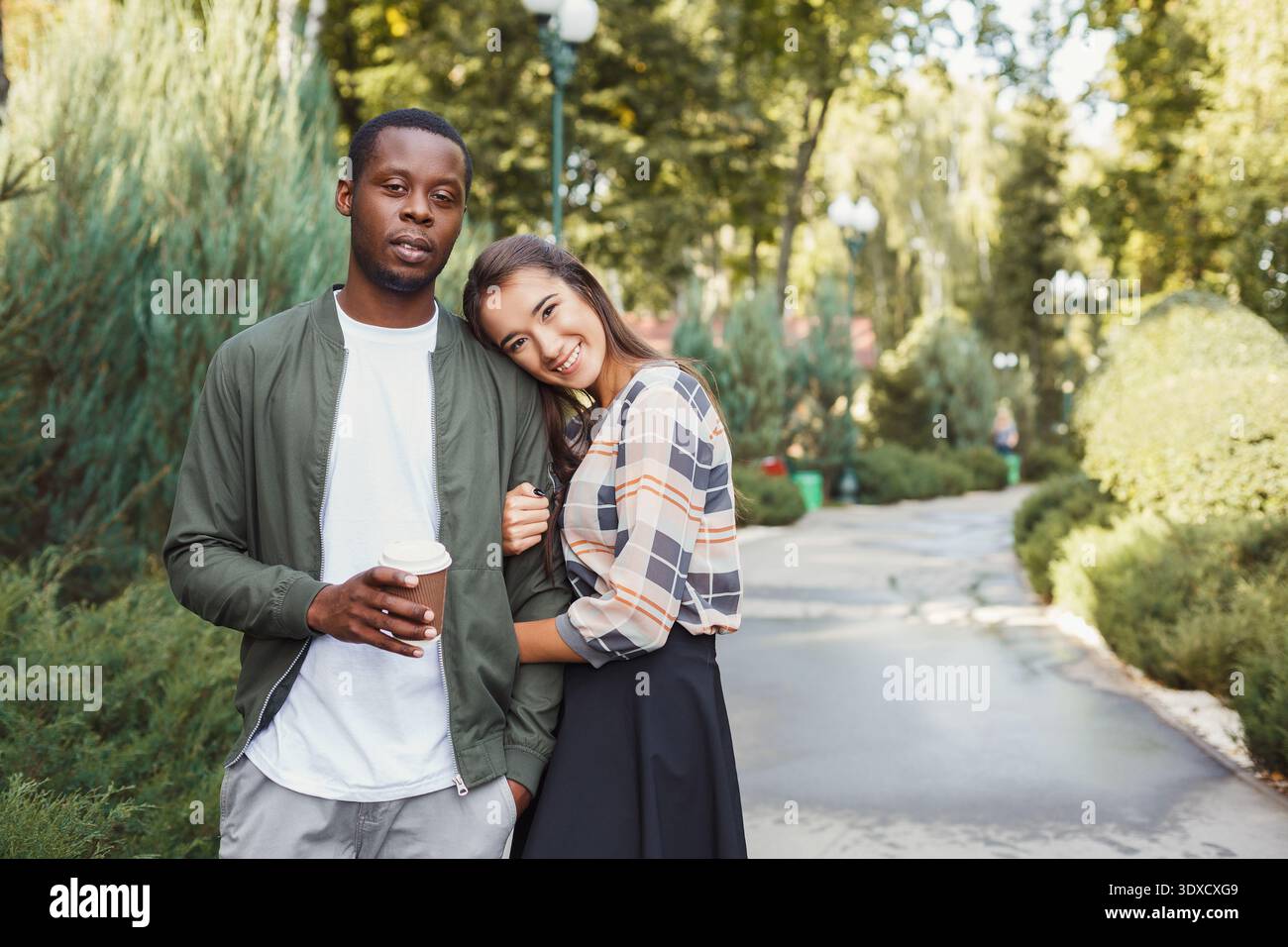 Coppia che si diverte insieme in un parco circondato da alberi e vegetazione Foto Stock