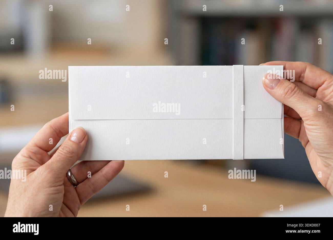 Mockup della busta con la fascetta in mano. Foto Stock